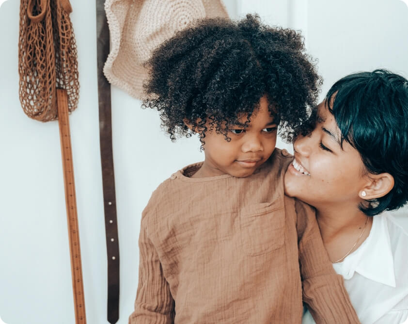 A mother and daughter hugging in front of a closet.