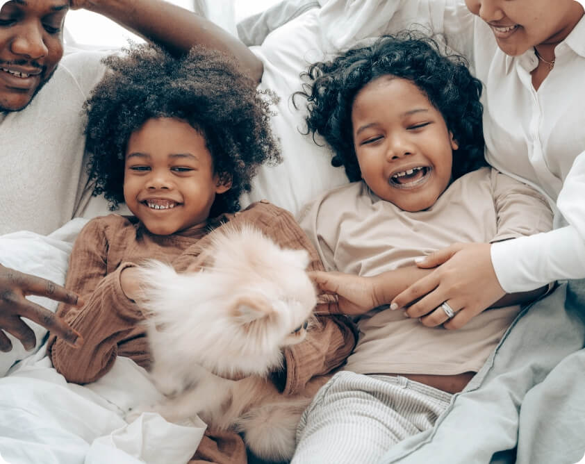 A family laying on a bed with a dog.
