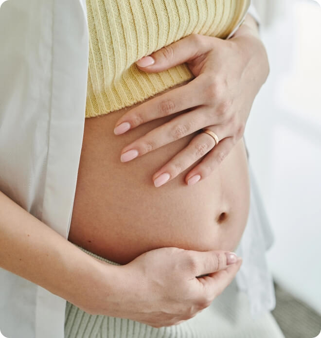 A pregnant woman with her hands on her stomach.