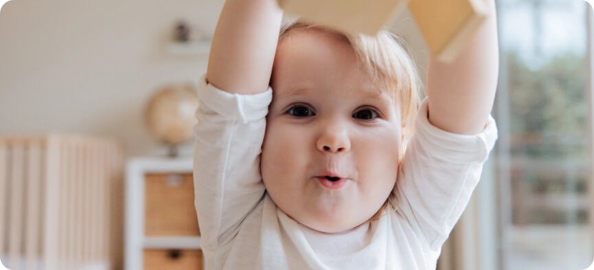 A baby holding up a box.