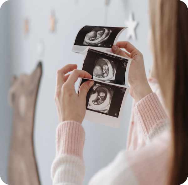 Woman holding 3 ultrasounds in baby room