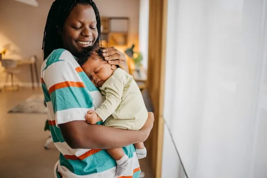 Mom holding baby near window