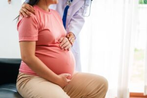 pregnant womans belly being support by a nurse at a pregnancy clinic