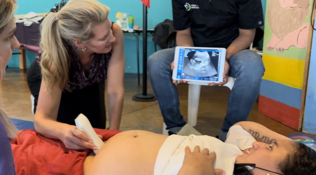 image of woman with portable ultrasound machine providing ultrasound of pregnant woman