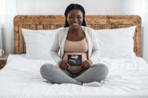 pregnant-woman-holding-ultrasound-pic-over-belly-on-bed